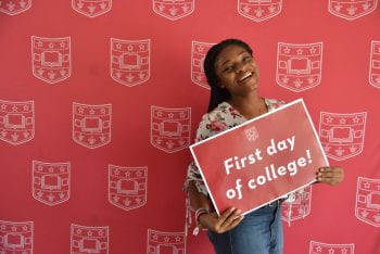 An undergrad student with sign "First day of college!".