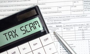 tax scam words on calculator display with tax forms